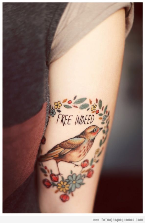 Tatuaje de un pájaro con las palabras free indeed en el brazo de un chico