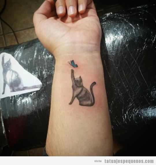 Tatuaje pequeño gato y mariposa en la muñeca