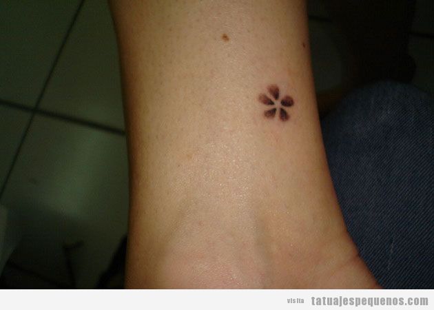 Tatuaje muy pequeño de una flor encima del tobillo