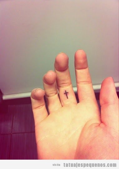 Tatuajes pequeños de cruz en el dedo corazón