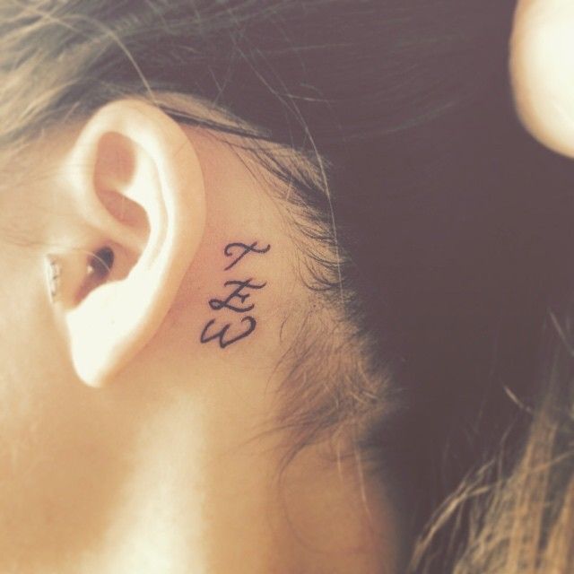 Tatuaje pequeño tres iniciales detrás oreja