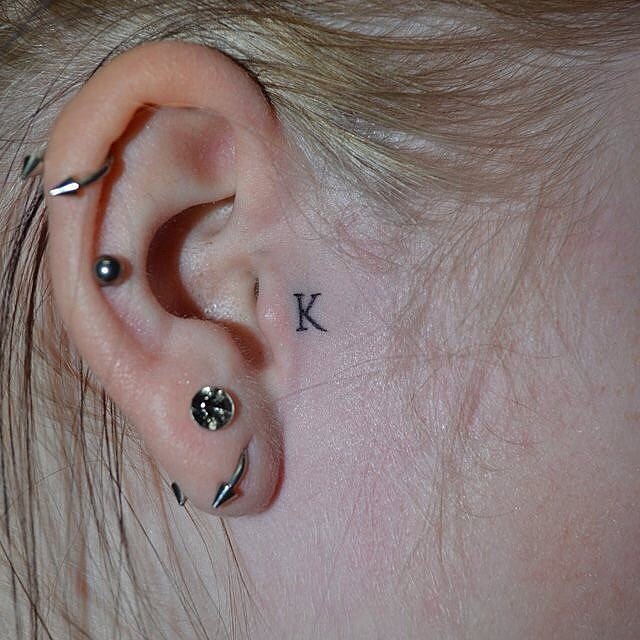 Tatuaje pequeño inicial K en oreja